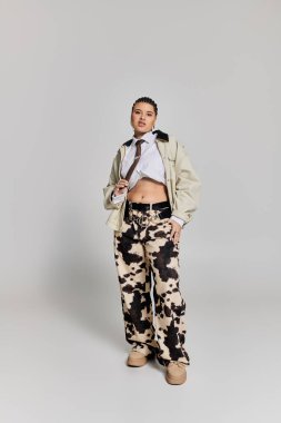 Genç bir kadın, eşsiz bir giysi ve minimalist bir ortamda cesur bir pozla moda yeteneğini sergiliyor..