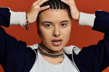 A fashionable young woman with braided hair confidently poses against a bold orange backdrop. clipart