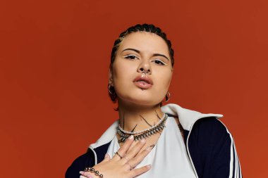 A young woman displays her trendy style with unique accessories against an orange backdrop. clipart