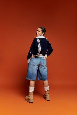 Moda kıyafetleri içinde genç bir kadın, kendine güvenen, modern şehir moda estetiğini somutlaştıran bir poz veriyor..