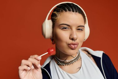 A young woman with braids and stylish accessories poses playfully with a lollipop and headphones. clipart