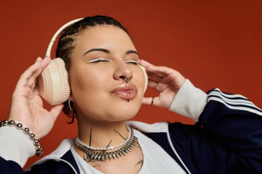 Modaya uygun özellikleri olan çekici genç bir kadın moda kulaklıklar takarken kendini kaybediyor..