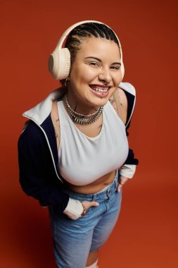 Kendine güvenen, kendine has saçları ve şık kıyafetleri olan genç bir kadın müzik dinlerken gülümsüyor..