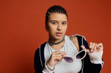 Şık genç kadın moda anlayışını şık güneş gözlükleri ve kendine güvenen ifadesiyle sergiliyor.