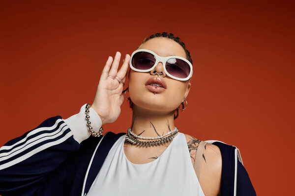 A fashionable young woman showcases her unique style while striking a confident pose indoors.