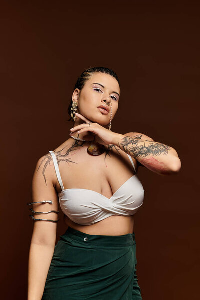 Уверенная молодая женщина в модном наряде элегантно позирует на коричневом фоне, выражая стиль.