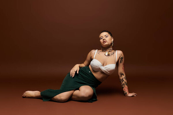A stylish young woman sits gracefully, flaunting her unique tattoos and confident art.