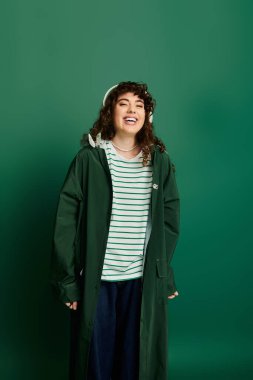 Genç bir kadın hayat dolu yeşil bir ortamda şık bir kıyafet giyerken mutluluk saçar..