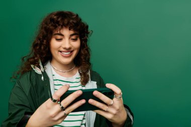 Gülümseyen kadın akıllı telefonuyla meşgul oluyor, şık bir moda ve canlı bir ortam sergiliyor..