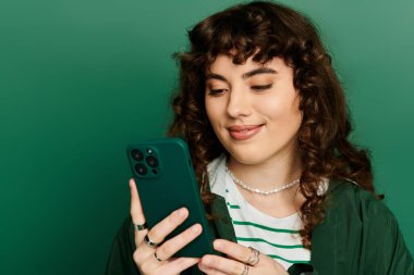 Tarz sahibi genç bir kadın akıllı telefonunu canlı bir fon üzerinde güvenli bir şekilde kullanır..