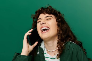 Genç ve şık bir kadın telefonuyla konuşurken neşe ve kahkaha ifade eder, mutluluk saçar..