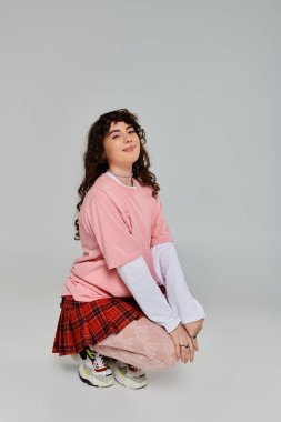 Genç bir kadın şık bir stüdyoda diz çöküp yaratıcı moda anlayışını ve duygularını sergiliyor..