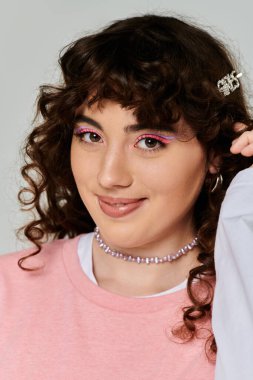 Pastel kıyafetli güzel bir kadın neşeli bir şekilde gülümserken moda makyajını sergiliyor.