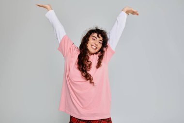 Neşeli genç bir kadın, moda anlayışını, neşeli kol hareketleriyle, duygu dolu bir şekilde gösteriyor..