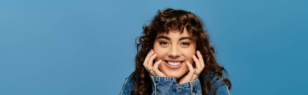 Молодая женщина излучает радость, выставляя напоказ свой уникальный стиль яркой синей стеной.