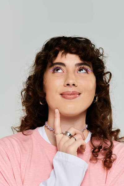 A fashionable young woman with curly hair shows an emotional and thoughtful expression while posing.