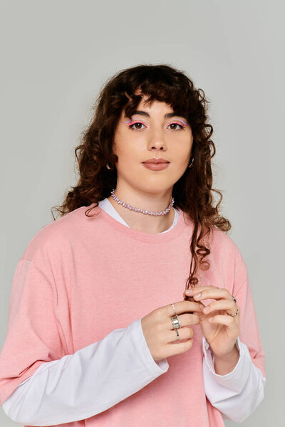 Шикарная молодая женщина демонстрирует эмоции, позируя в гладкой, минималистской обстановке.