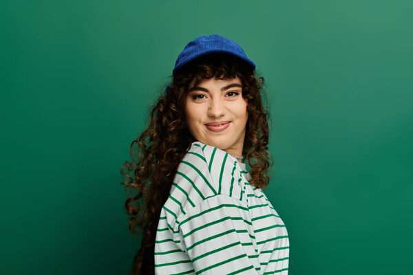 Young woman wears a striped shirt and cap while expressing her emotions with a playful smile.