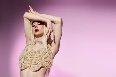 Şık bir travesti, pastel bir arka plana karşı sanatsal bir poz verir, şık giyinir..