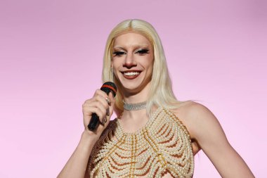 Kendine güvenen genç bir travesti sahnede sahneye çıkıyor, mikrofonla havalı ve yetenekli bir şekilde..