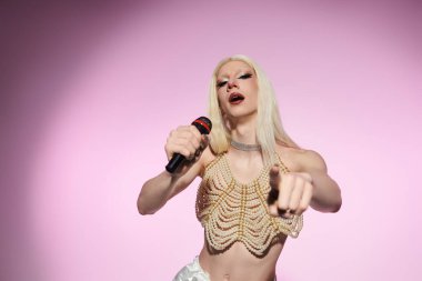 Şık bir travesti, güvenli bir şekilde mikrofona şarkı söylerken ışıldar..