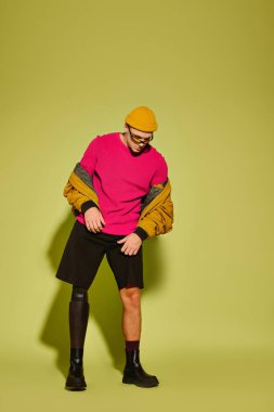 Kendine güvenen genç adam şık bir şekilde poz veriyor, şık görünüşünü ve protez bacağını vurguluyor..