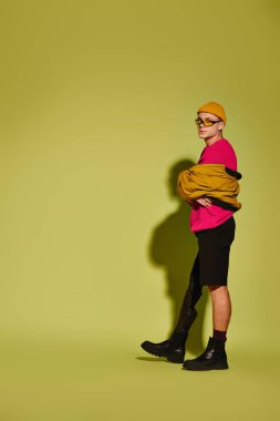 Yakışıklı genç bir adam kendine güvenerek şık bir şekilde poz verir cesur yeşil bir zemine karşı.