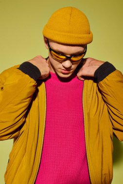 Yakışıklı genç adam şık bir şekilde poz veriyor. Parlak bir arka plana karşı cesur bir kıyafet..