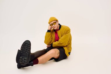 Kendine güveni tam bir genç adam, bir stüdyoda protez bacağını göstererek şık bir şekilde poz veriyor..