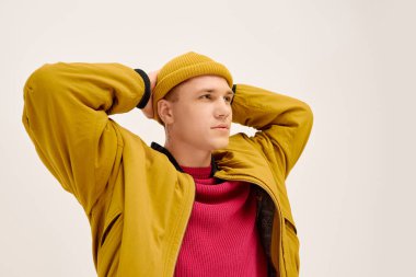 Yakışıklı genç bir adam çağdaş bir stüdyo ortamında modaya uygun kıyafetler sergiliyor..