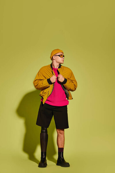 Молодой человек с протезной ногой стильно позирует в красочной студии, принимая разнообразие.