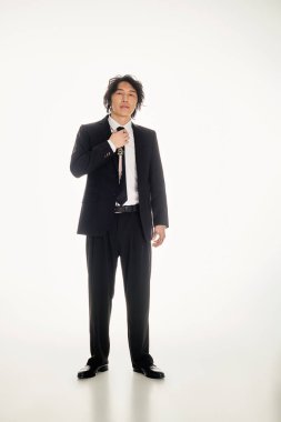 Yakışıklı Asyalı genç adam şık giyinip, çağdaş modayı sergilerken özgüven yayıyor..