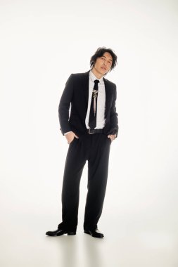 Yakışıklı Asyalı genç adam modern bir ortamda modaya uygun bir şekilde duruyor..