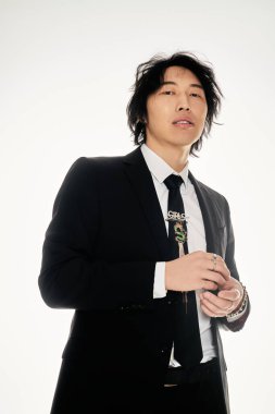 Kendine güvenen genç adam, stüdyo ortamında modern moda ve şık tarzını sergiliyor..