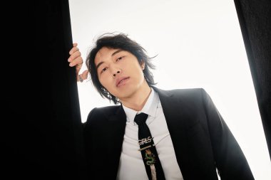 Havalı Asyalı genç adam moda anlayışını moda ortamında sergiliyor..