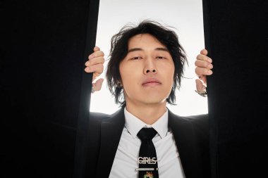 Takım elbiseli yakışıklı genç Asyalı adam modern şehir modasını sergiliyor..