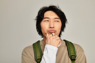 Şık bir genç adam modern bir arka plana karşı düşünceli bir ifade sergiliyor..