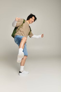 Moda kıyafetleri içinde, genç Asyalı bir adam benzersiz tarzını sergilerken neşe içinde poz veriyor..