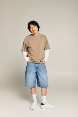 Yakışıklı Asyalı genç adam hoş bir gülümseme takınarak şık kıyafetini sergiliyor..