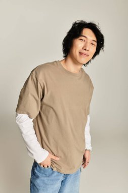 Şık bir Asyalı genç adam modern bir stüdyoda kendine güvenerek duruyor..