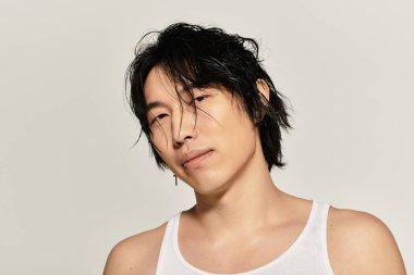 Karizmatik genç Asyalı erkek rahat duruşu ve zahmetsiz tarzıyla modern zarafet sergiliyor..