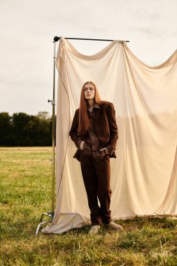 Genç bir adam, altın saatinde yumuşak bir kumaşa karşı şık kıyafetler içinde poz verir..