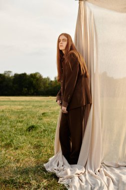 Uzun saçlı, yakışıklı bir adam, şık giyiniyor. Resimli bir arkaplan karşısında..