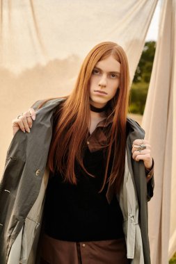 Uzun saçlı genç adam özgüvenle sunar şık görünümünü, güzelliklerle çevrili..