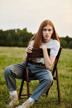 Şık giyinmiş genç, yakışıklı bir adam, sakin bir açık hava ortamında düşünceli bir şekilde oturur..