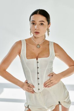 Güzel bir jimnastikçi, modaya uygun beyaz elbiseler giyerken esnekliğini ve zarafetini gösteriyor..