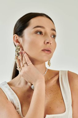 Büyüleyici özellikleri olan genç bir kadın zarif poz verir, şık takılar takar ve şık kıyafetler giyer..