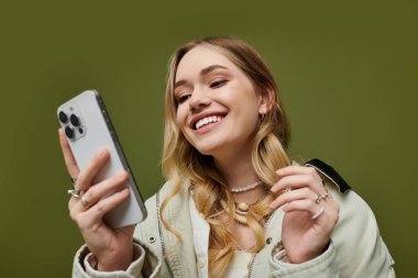 Havalı bahar kıyafetleri içinde şık genç bir kadın telefonuyla mutlu mesut meşgul oluyor..