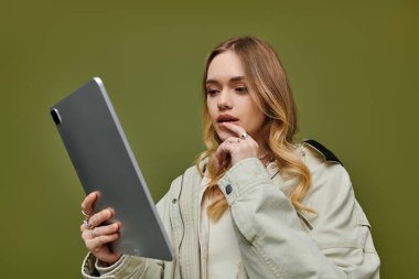 Şık giyinmiş genç bir kadın dijital keşiflere dalmış tabletine odaklanıyor..