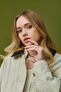 Çekici genç kadın zarif poz veriyor, şık bahar kıyafetlerini ve neşeli cazibesini vurguluyor..